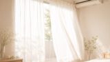 白いレースのカーテンが朝の風で揺れる窓辺と壁のエアコン