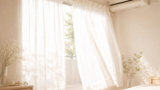 白いレースのカーテンが朝の風で揺れる窓辺と壁のエアコン
