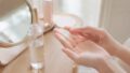 木の鏡台で化粧水を手のひらになじませる女性の手元