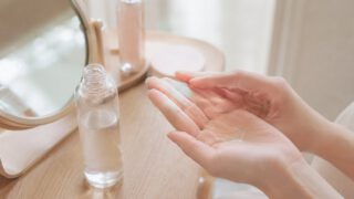 木の鏡台で化粧水を手のひらになじませる女性の手元
