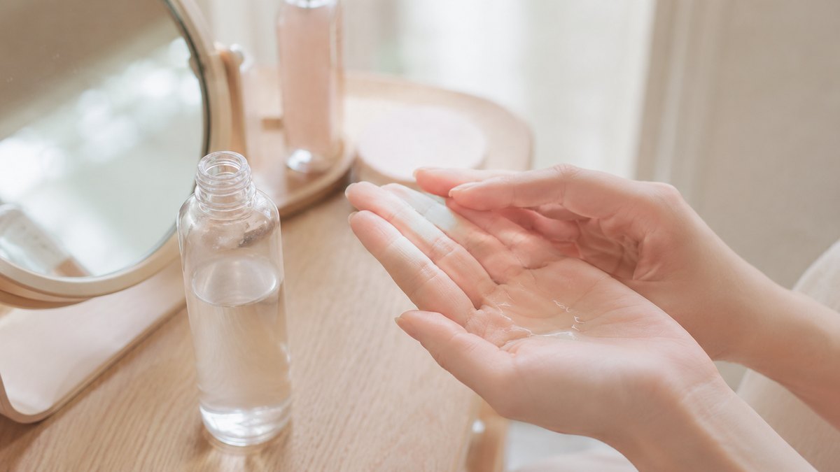 木の鏡台で化粧水を手のひらになじませる女性の手元