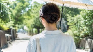 日傘を差して並木道を歩く後ろ姿、まとめた髪とうなじ
