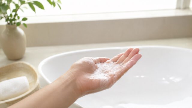 洗面器の上で泡立てたクレンジングオイルを持つ手